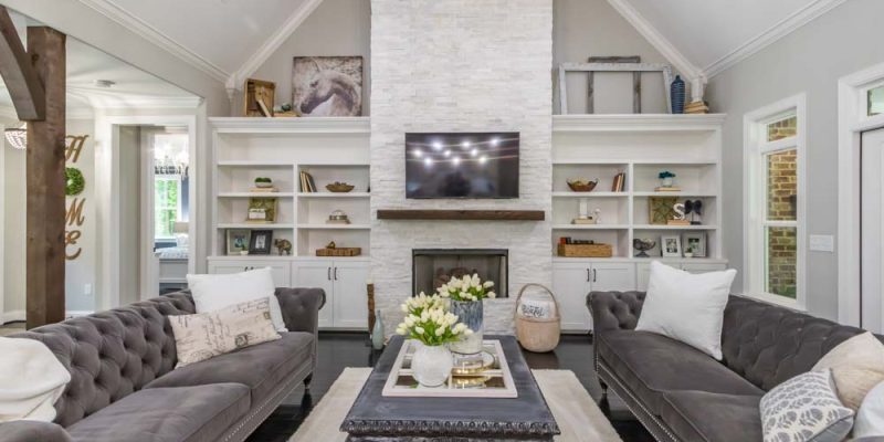A modern living room featuring a stone fireplace, built-in shelving, and plush sofas arranged around a central coffee table, with decor elements adding warmth and personality to the space.