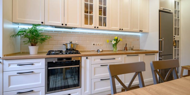 A warm and inviting kitchen space with white cabinetry, subway tile backsplash, and wooden countertops, complemented by modern appliances and natural light.