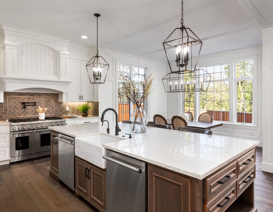 A spacious kitchen featuring a large island with a farmhouse sink, elegant pendant lighting, and a dining area with large windows, blending functionality and style.