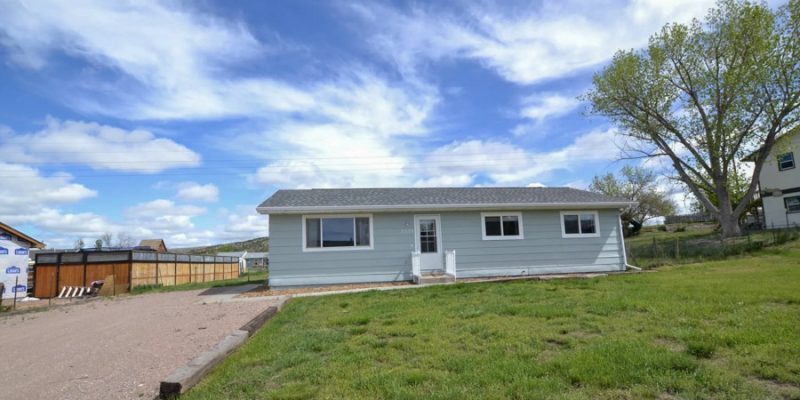 A renovated mobile home exterior featuring modern gray siding and a quaint front entrance, highlighting the quality craftsmanship of the remodeling work.