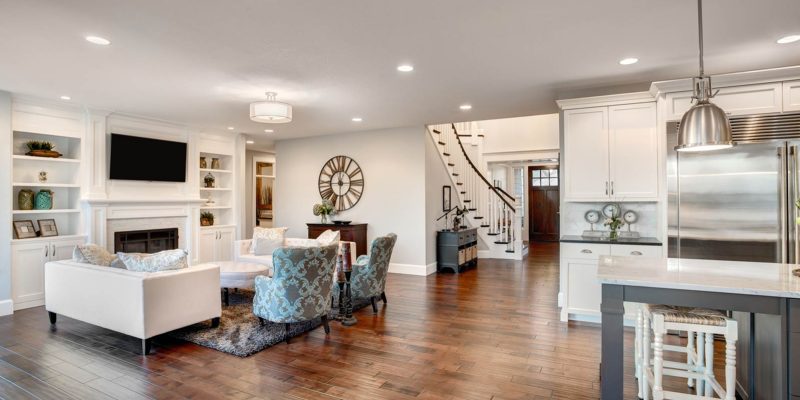 Spacious living area with custom built-in shelves, elegant seating, and a seamless transition to a gourmet kitchen, highlighting expansive home renovation.