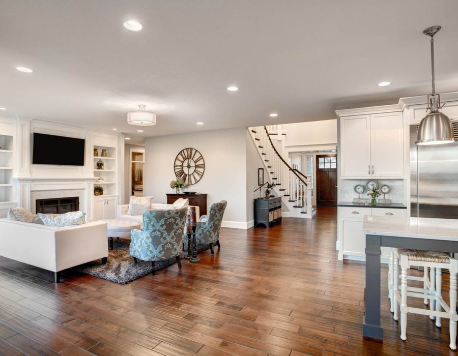 Spacious living area with custom built-in shelves, elegant seating, and a seamless transition to a gourmet kitchen, highlighting expansive home renovation.